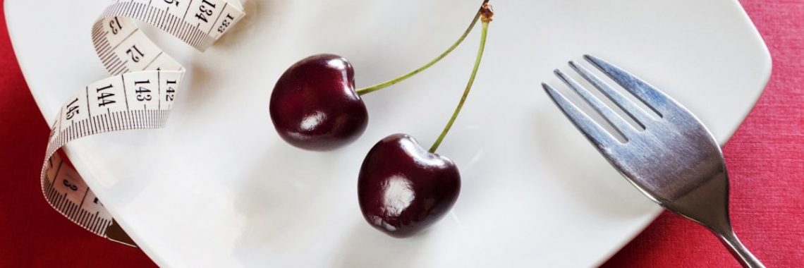 Diet white plate with centimeter, cherry, fork